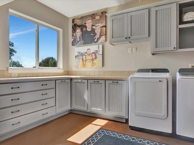 laundry room with cabinet space, dark tile patterned flooring, and washing machine and dryer