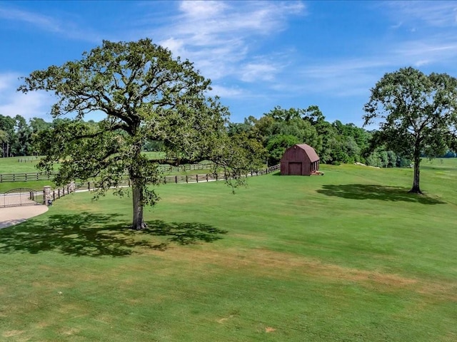 view of yard featuring a barn, an outdoor structure, and fence