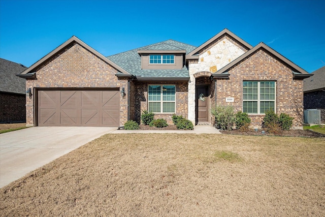 view of front of house featuring central AC unit, a front yard, and a garage