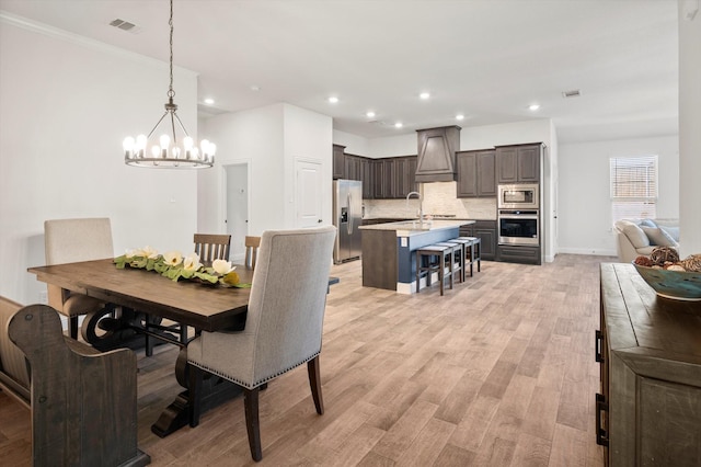 dining space featuring light hardwood / wood-style floors, an inviting chandelier, and sink