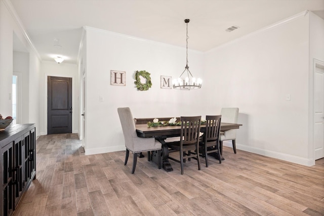 dining area featuring light hardwood / wood-style floors, an inviting chandelier, and crown molding