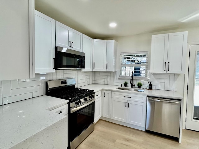 kitchen with decorative backsplash, white cabinetry, sink, and appliances with stainless steel finishes