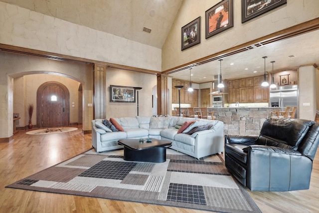 living room featuring high vaulted ceiling and light wood-type flooring