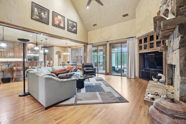 living room featuring ceiling fan, high vaulted ceiling, and light hardwood / wood-style floors