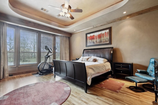 bedroom featuring a tray ceiling, light hardwood / wood-style flooring, and ceiling fan