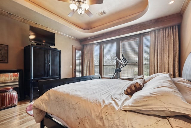 bedroom with a tray ceiling, ceiling fan, and light hardwood / wood-style flooring