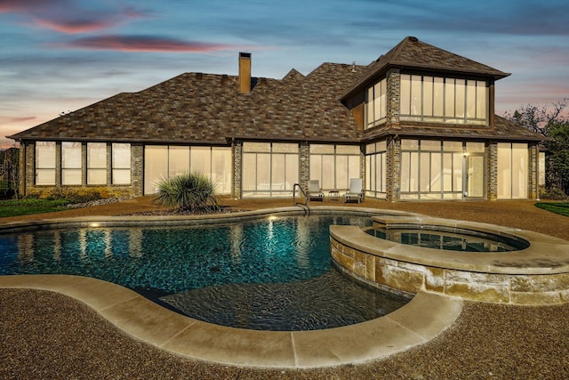 pool at dusk featuring an in ground hot tub and a patio