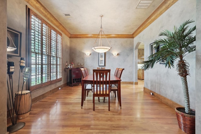 dining area with crown molding and light wood-type flooring