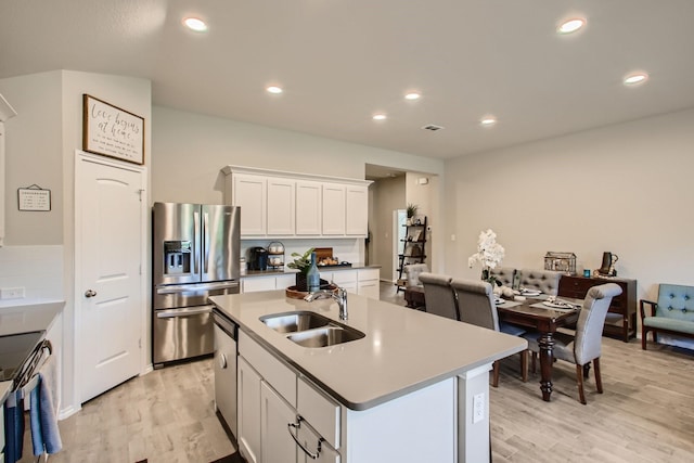 kitchen featuring white cabinets, sink, stainless steel appliances, and a kitchen island with sink