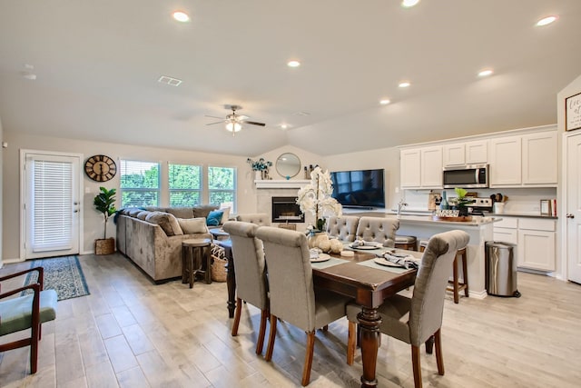 dining area with vaulted ceiling, light hardwood / wood-style flooring, ceiling fan, and sink