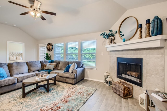 living room featuring a fireplace, vaulted ceiling, light hardwood / wood-style flooring, and ceiling fan