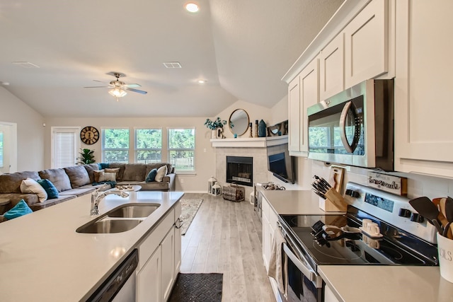 kitchen featuring white cabinets, stainless steel appliances, vaulted ceiling, and sink