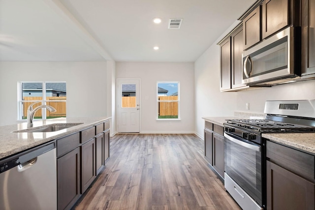 kitchen with a healthy amount of sunlight, light stone countertops, sink, and stainless steel appliances