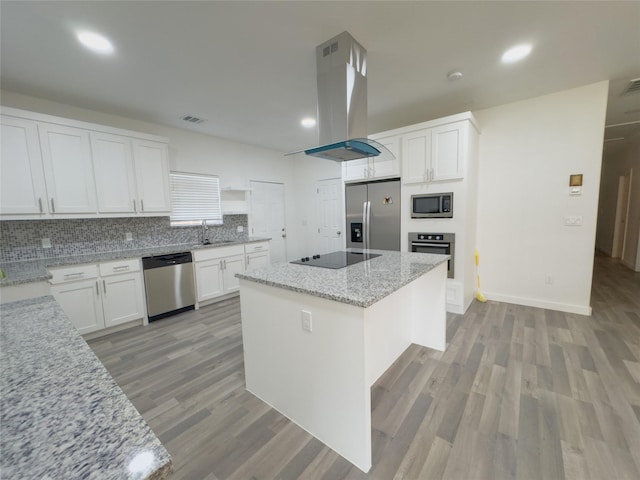 kitchen featuring appliances with stainless steel finishes, white cabinetry, island range hood, light stone countertops, and a kitchen island