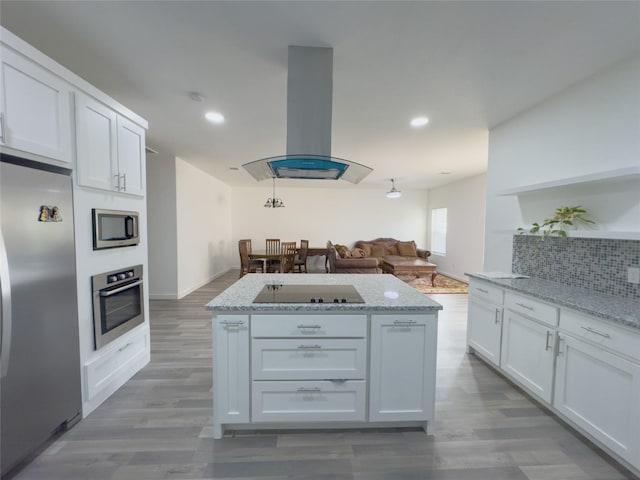 kitchen with stainless steel appliances, island exhaust hood, light stone countertops, and white cabinets