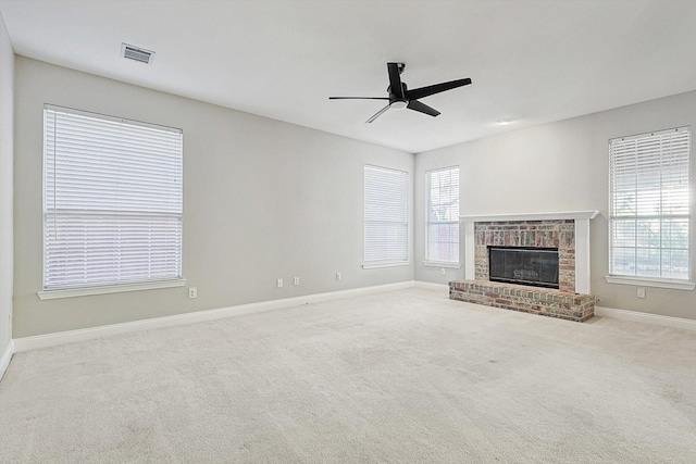 unfurnished living room with ceiling fan, light colored carpet, a healthy amount of sunlight, and a brick fireplace