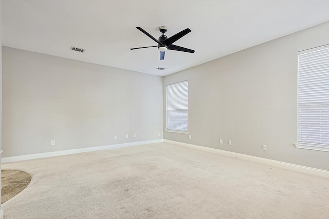 unfurnished room featuring ceiling fan, plenty of natural light, and light carpet