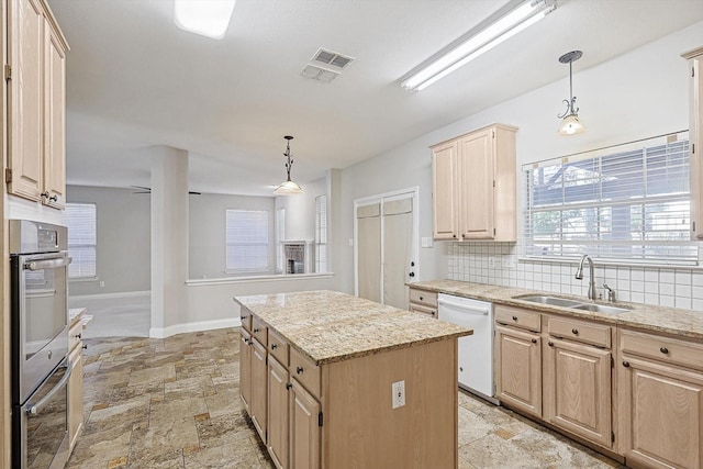 kitchen featuring dishwasher, sink, a kitchen island, and light brown cabinets