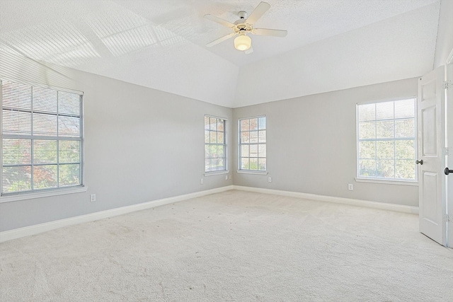 carpeted empty room with a wealth of natural light, vaulted ceiling, and ceiling fan