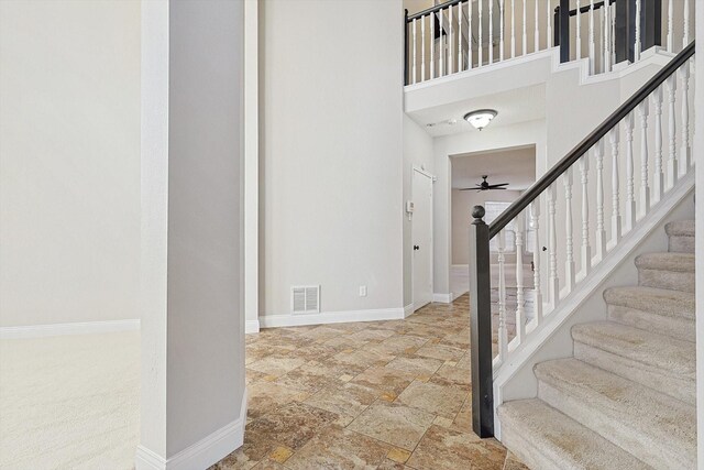 entryway featuring ceiling fan and a high ceiling