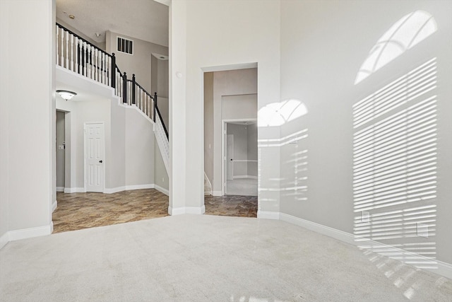 interior space featuring carpet flooring and a towering ceiling