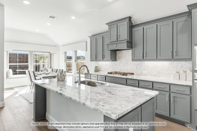 kitchen with lofted ceiling, stainless steel gas stovetop, gray cabinetry, and sink