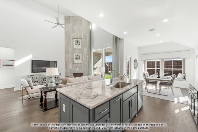 kitchen featuring a center island with sink, gray cabinets, light stone countertops, and sink