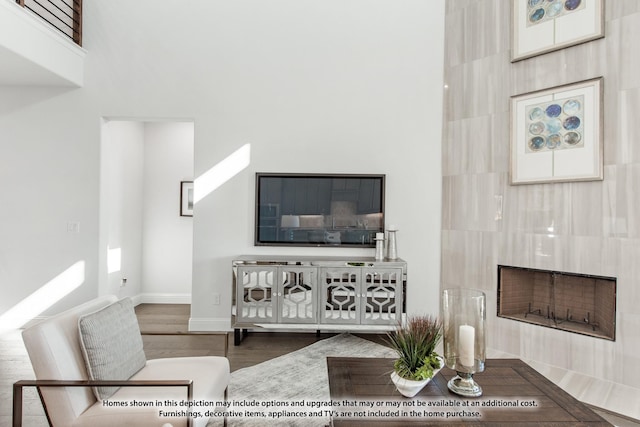 living room with a large fireplace, dark hardwood / wood-style flooring, and a towering ceiling