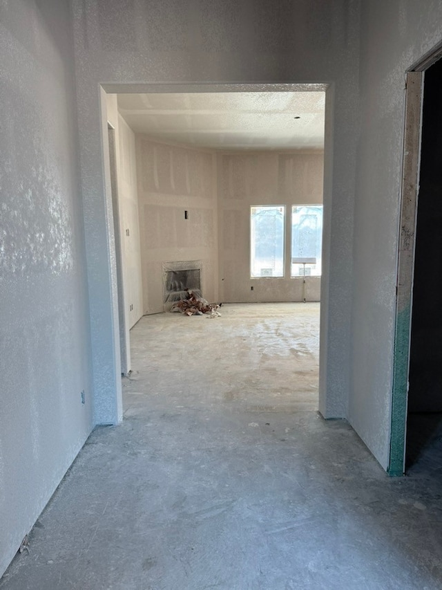 corridor featuring a textured wall and unfinished concrete flooring