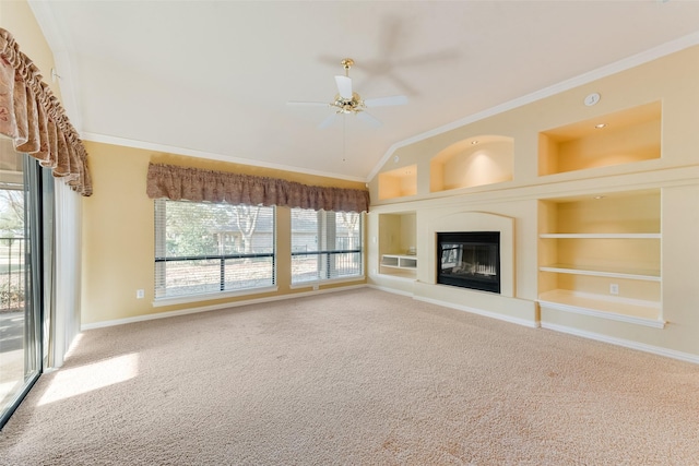 unfurnished living room featuring carpet flooring, built in shelves, ceiling fan, and ornamental molding