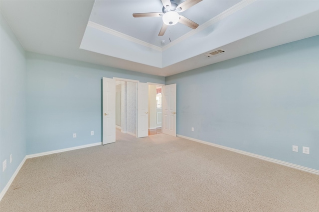 unfurnished bedroom with a tray ceiling, ceiling fan, carpet, and ornamental molding