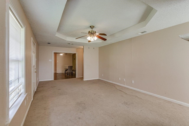 carpeted spare room with ceiling fan, a raised ceiling, and a textured ceiling