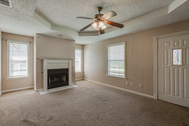 unfurnished living room featuring a textured ceiling, ceiling fan, a raised ceiling, and light carpet