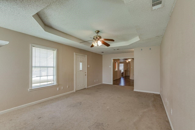 unfurnished room with carpet flooring, a tray ceiling, and ceiling fan