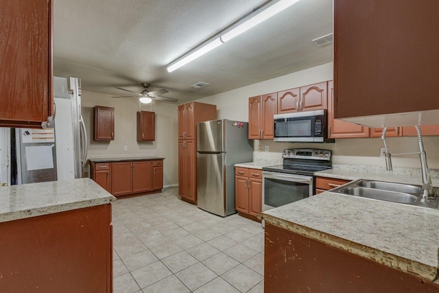 kitchen featuring appliances with stainless steel finishes, a textured ceiling, ceiling fan, and sink