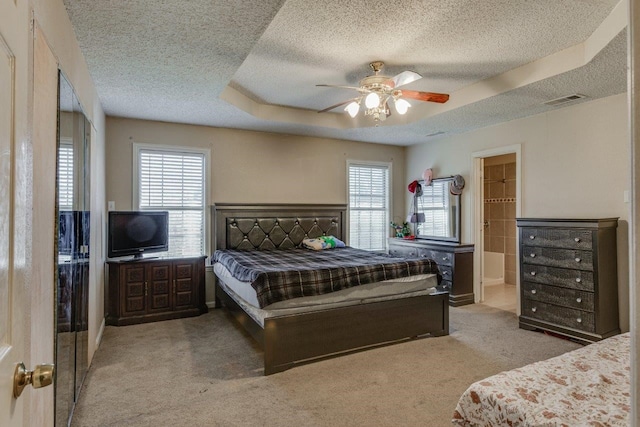 carpeted bedroom featuring a textured ceiling, a tray ceiling, and ceiling fan