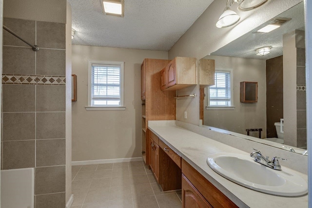 bathroom featuring vanity, a healthy amount of sunlight, a textured ceiling, and toilet