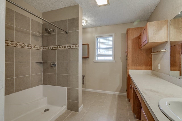 bathroom featuring a tile shower, vanity, and a textured ceiling