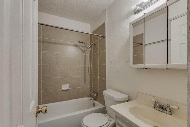 full bathroom with vanity, toilet, a textured ceiling, and tiled shower / bath