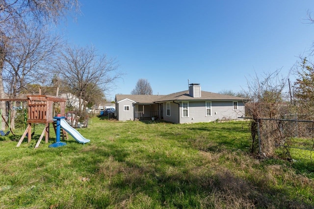 back of property featuring a playground and a lawn