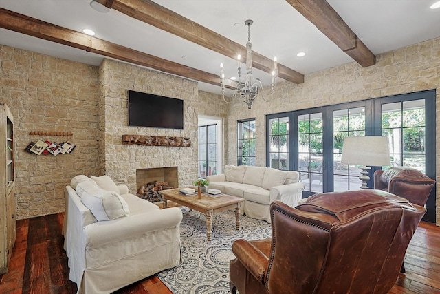 living room featuring dark hardwood / wood-style floors, a fireplace, a chandelier, and beamed ceiling