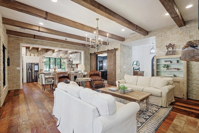 living room featuring an inviting chandelier, hardwood / wood-style floors, beam ceiling, and a barn door