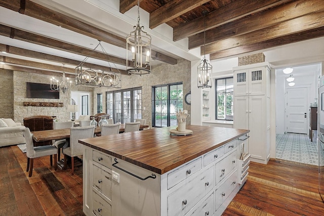 kitchen featuring decorative light fixtures, wooden counters, white cabinets, and a center island