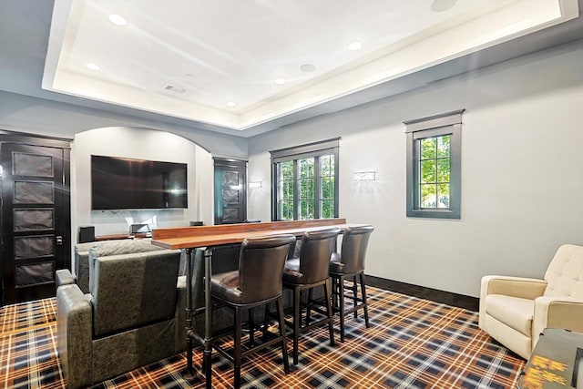 home theater with a raised ceiling, a healthy amount of sunlight, and bar area