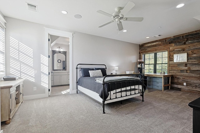 carpeted bedroom with connected bathroom, wooden walls, and ceiling fan