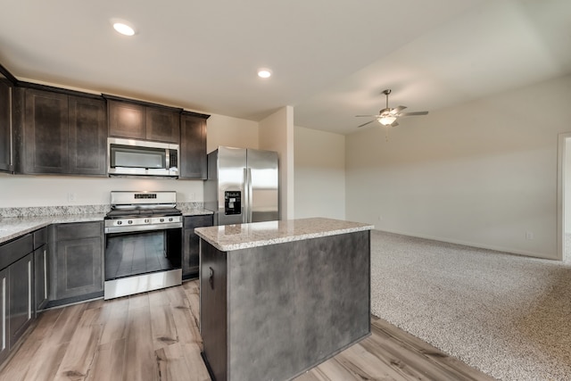 kitchen featuring light stone countertops, ceiling fan, a center island, light hardwood / wood-style flooring, and appliances with stainless steel finishes