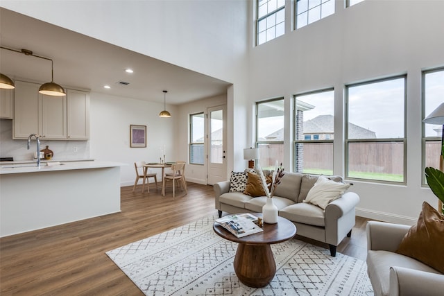 living room featuring recessed lighting, visible vents, a high ceiling, dark wood-type flooring, and baseboards