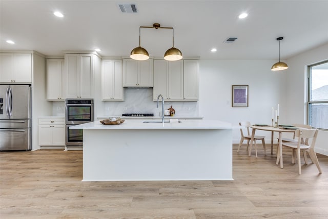 kitchen with light countertops, hanging light fixtures, visible vents, appliances with stainless steel finishes, and a sink