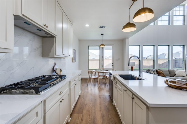 kitchen featuring light stone counters, stainless steel appliances, visible vents, hanging light fixtures, and white cabinets