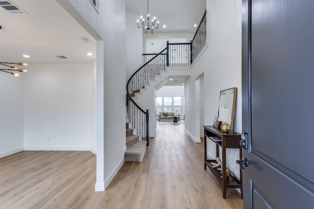 foyer featuring a notable chandelier, visible vents, baseboards, stairs, and light wood-type flooring